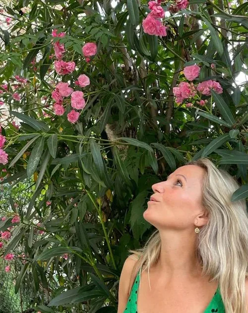 Nathalie kijkt omhoog naar een bloeiende struik in de tuin