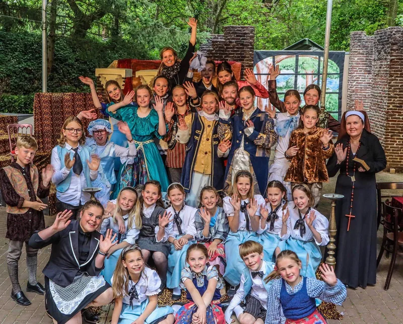 Grote groep kinderen in kostuum poseert buiten na afloop van de voorstelling