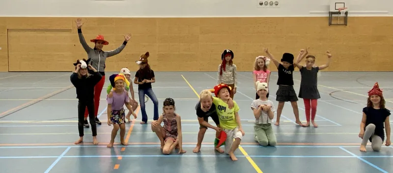 Kinderen in kostuum spelen verspreid over de vloer van de gymzaal